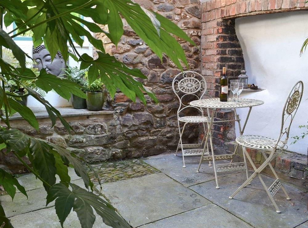 Enclosed partly covered courtyard with patio and garden furniture at Jalna in Stratton, near Bude, Cornwall