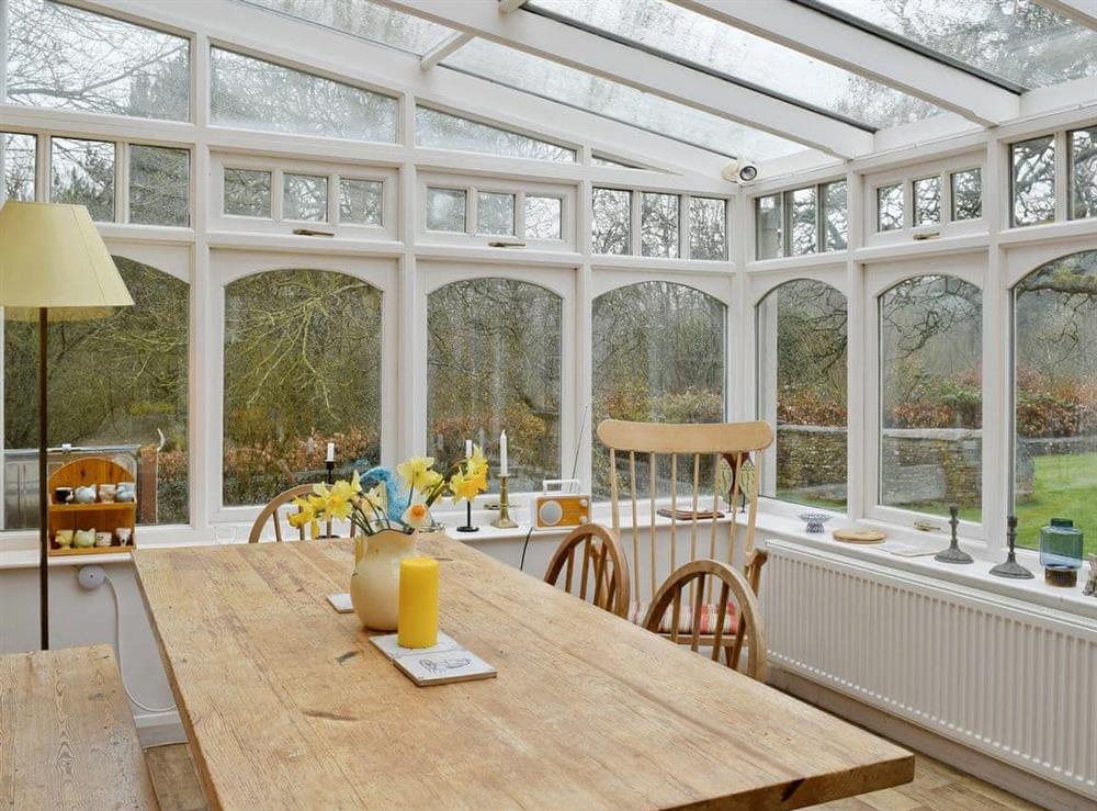 Large dining table in the conservatory at Jubilee Cottage in Church Enstone, near Chipping Norton, Oxfordshire