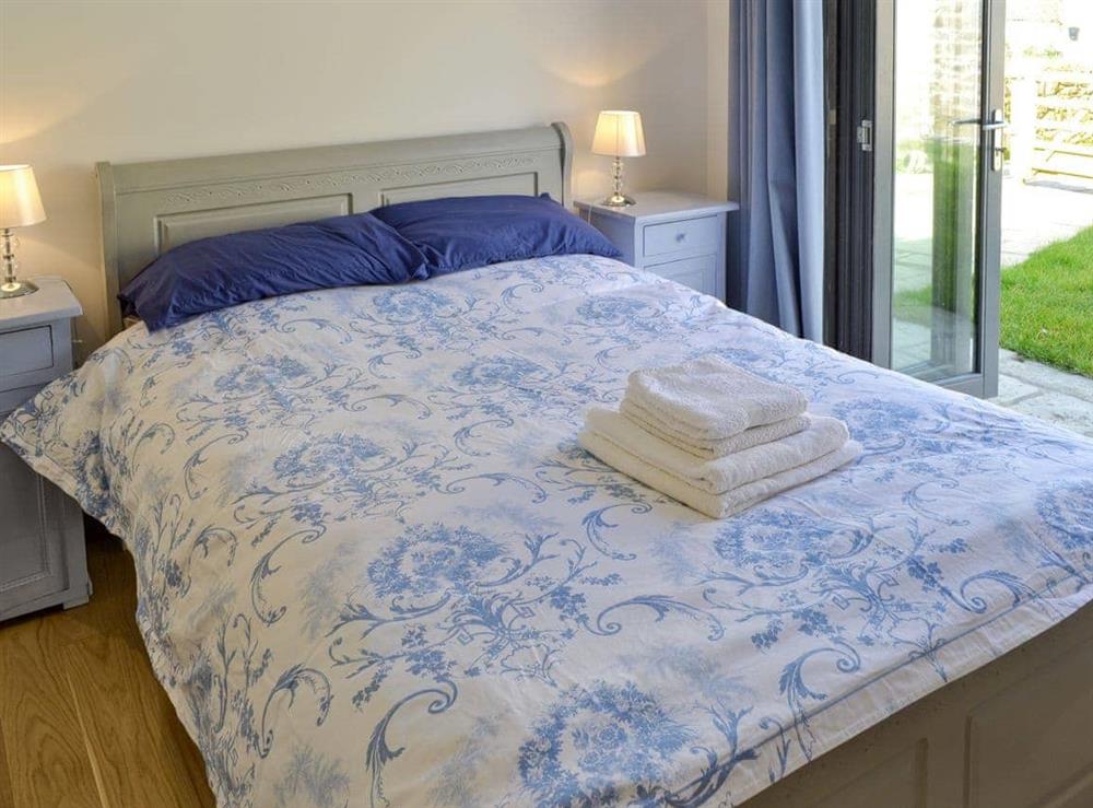 Comfortable double bedroom with bi-fold doors and en-suite shower room at Kataluma in Praa Sands, near Penzance, Cornwall