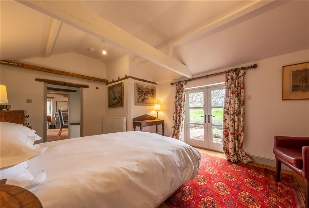Bedroom one with french doors to the garden, with beautiful views of the parkland at Keepers Cottage, Wolterton