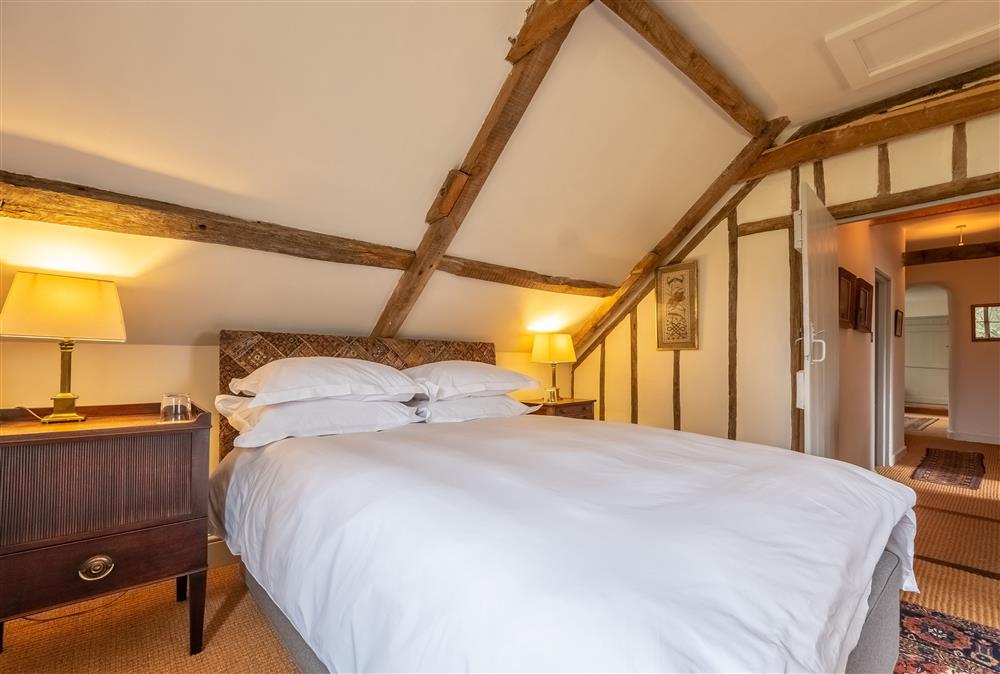 Bedroom three with a 5’ king-size bed and exposed beams at Keepers Cottage, Wolterton