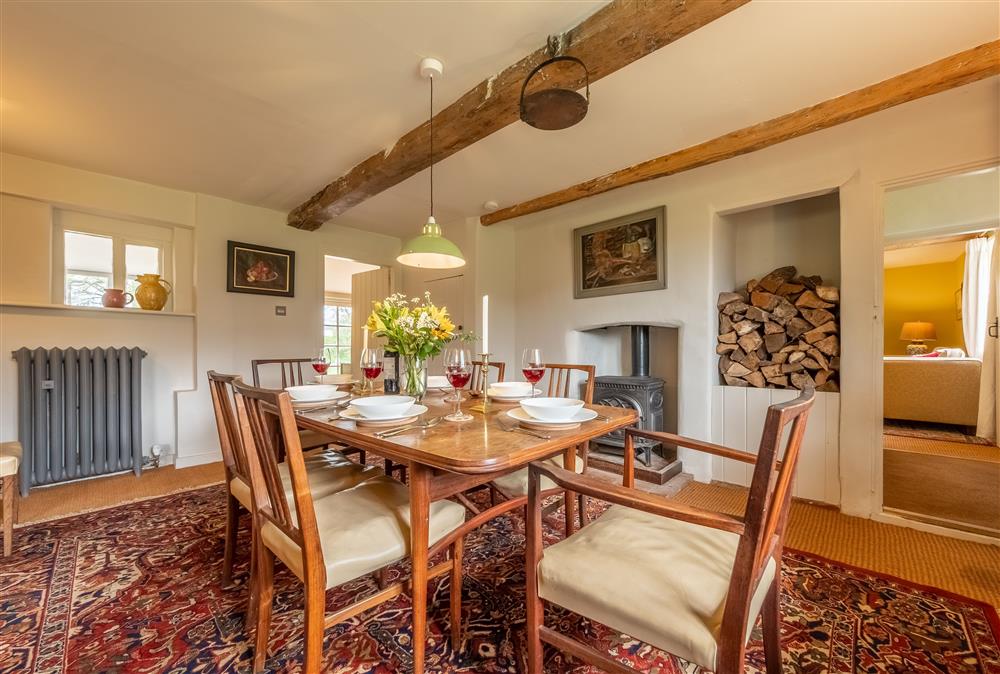 Dining room with a wood burning stove and exposed beams at Keepers Cottage, Wolterton