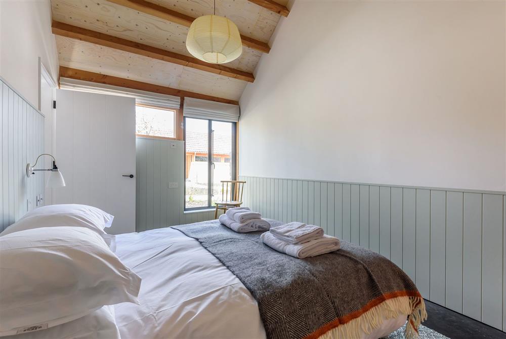 Bedroom one with a 5’ king-size bed and exposed beams throughout at Kittwhistle, Dorchester