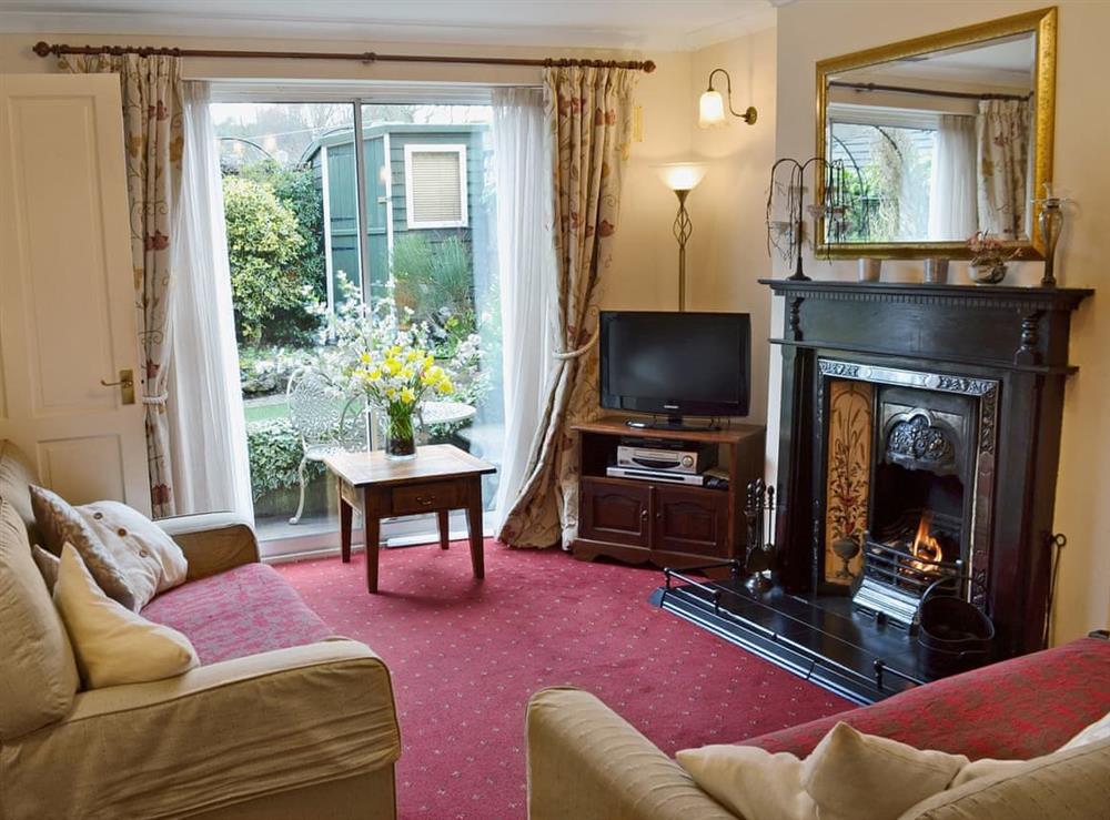 Living room with open fire and patio doors at Lace Cottage in Ashbourne, Derbyshire