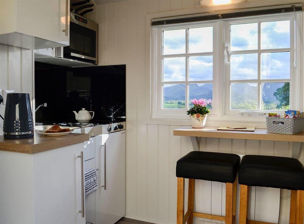 Compact kitchen and adjacent dining area at Lake View Shepherds Hut in Keswick, Cumbria