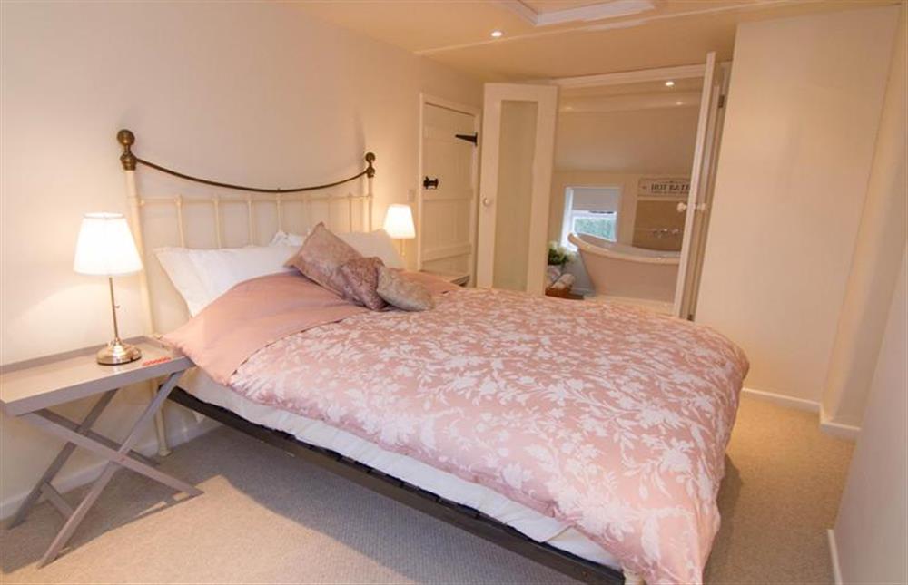 First floor:  Master bedroom with king-size wrought iron bed and glass doors to en-suite at Lambert Cottage, Snettisham near Kings Lynn