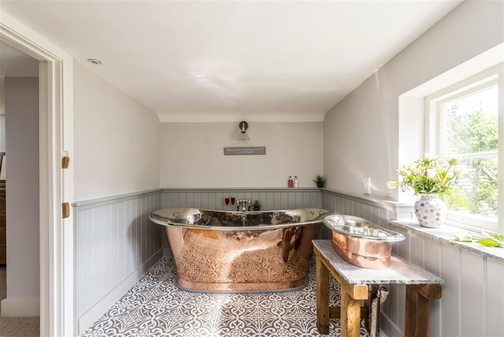 En-suite bathroom with copper bath and wash basin at Lanes End Cottage, Dorchester
