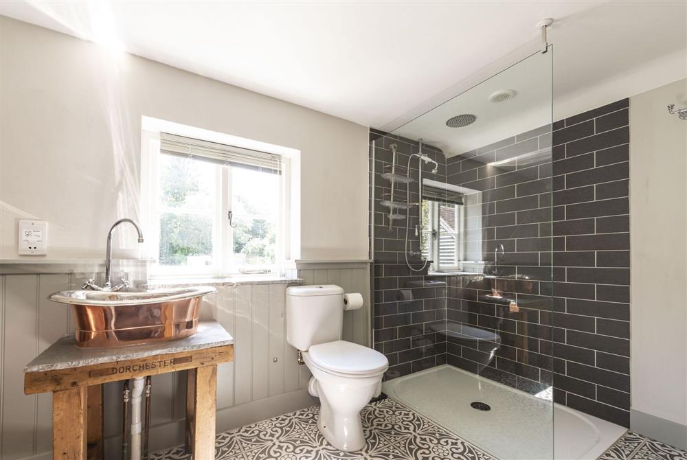 En-suite bathroom with copper bath, wash basin and walk-in shower at Lanes End Cottage, Dorchester
