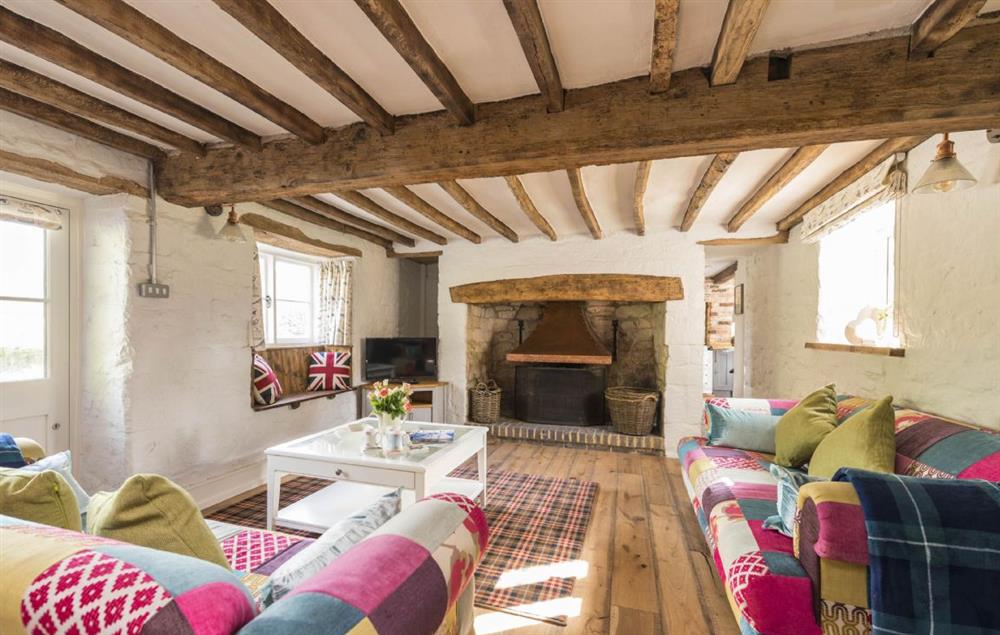 Spacious sitting room with open fire and exposed beams at Lanes End, Lower Wraxall