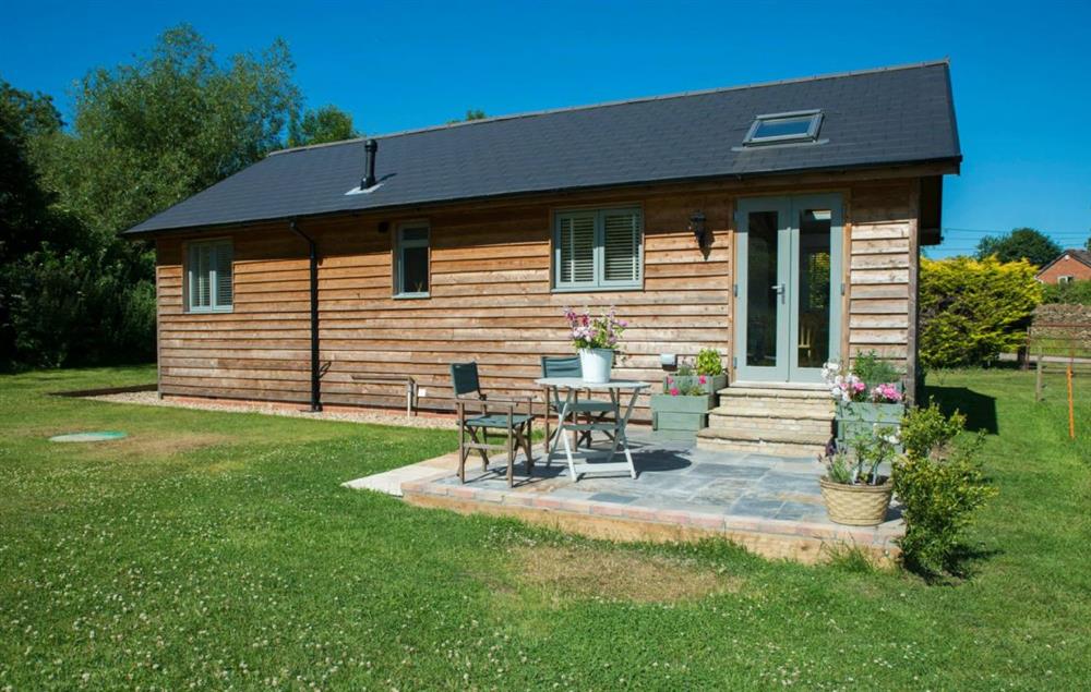 Large lawned meadow garden with patio and garden furniture at Larch Barn, North Perrott