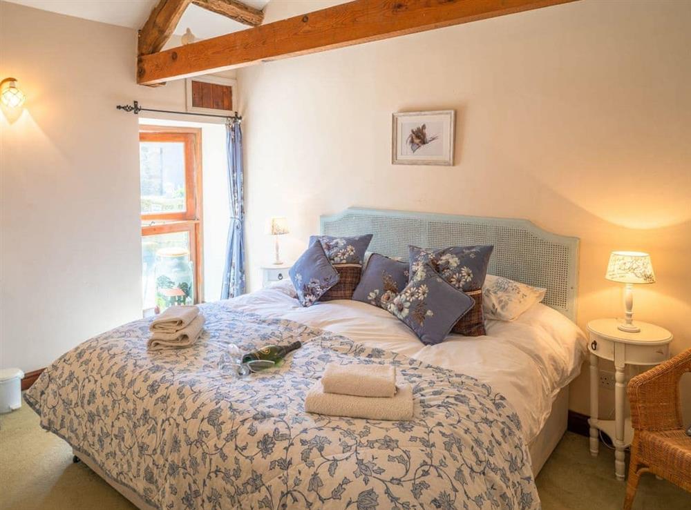 Relaxing double bedroom with exposed wood beams at Bridge Cottage, 