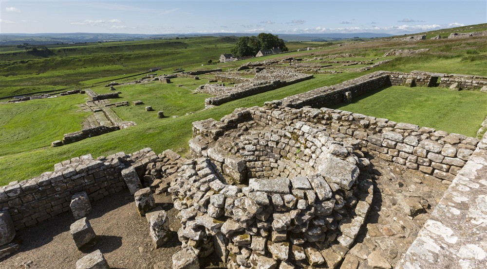 A view over grassland with low-lying ruins in the middle distance and foreground with blue skies above at Laundry Cottage in Morpeth, Northumberland