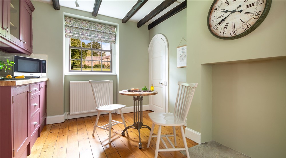 The kitchen with a microwave and small breakfast table for two at Laundry Cottage in Morpeth, Northumberland