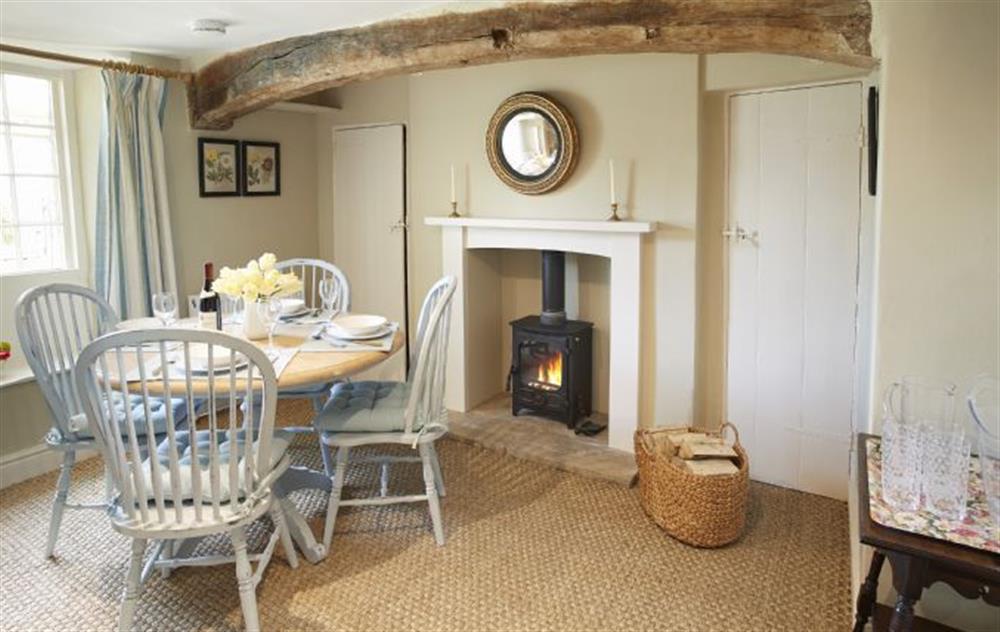 Dining room with exposed wooden beams and wood burning stove at Librarians Cottage, Coneysthorpe