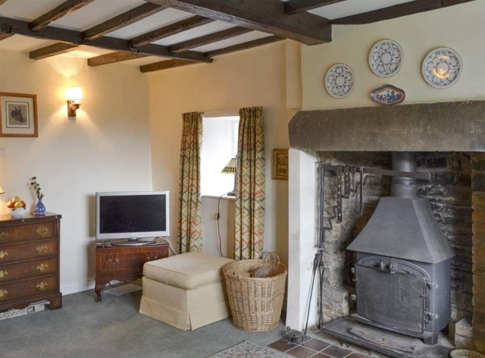 Feature fireplace with wood-burner and exposed wood beamed ceiling in living room at Lilac Cottage in Sinnington, near Pickering, North Yorkshire