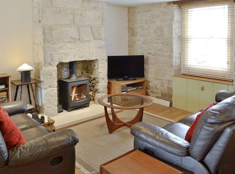 Cosy lounge with wood-burner and exposed stone fireplace at Lime Cottage in Portland, near Weymouth, Dorset