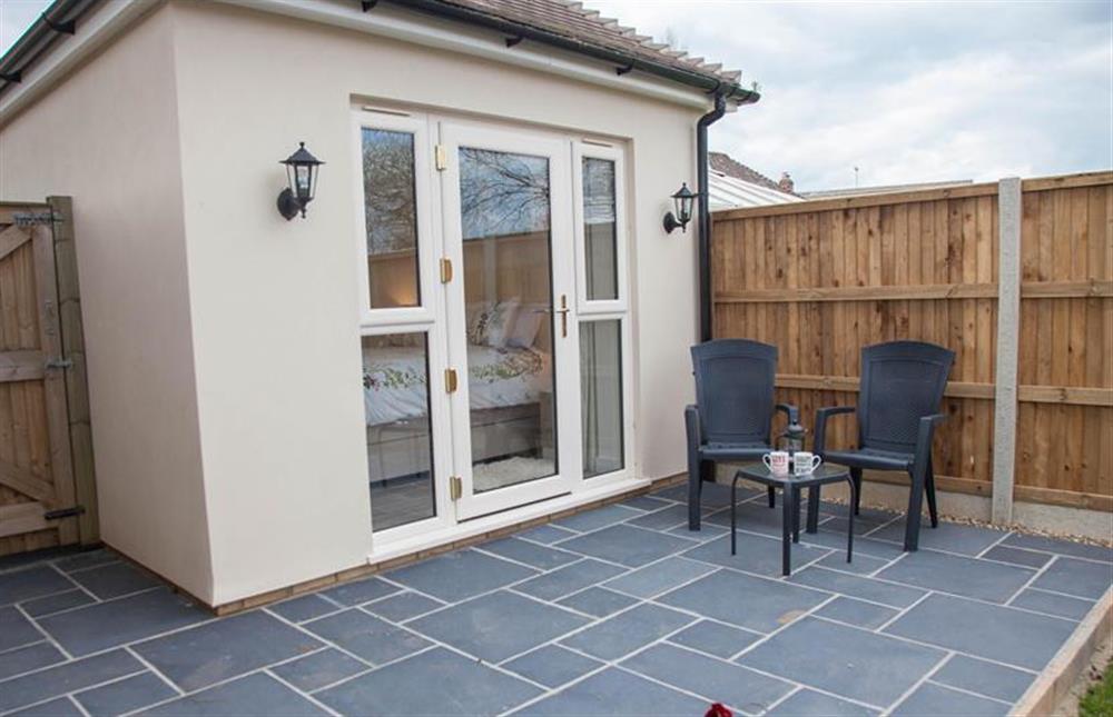 Rear garden:  Fully enclosed with patio area with table and seating for two leading  to lawned area at Little Birches, Roydon near Kings Lynn