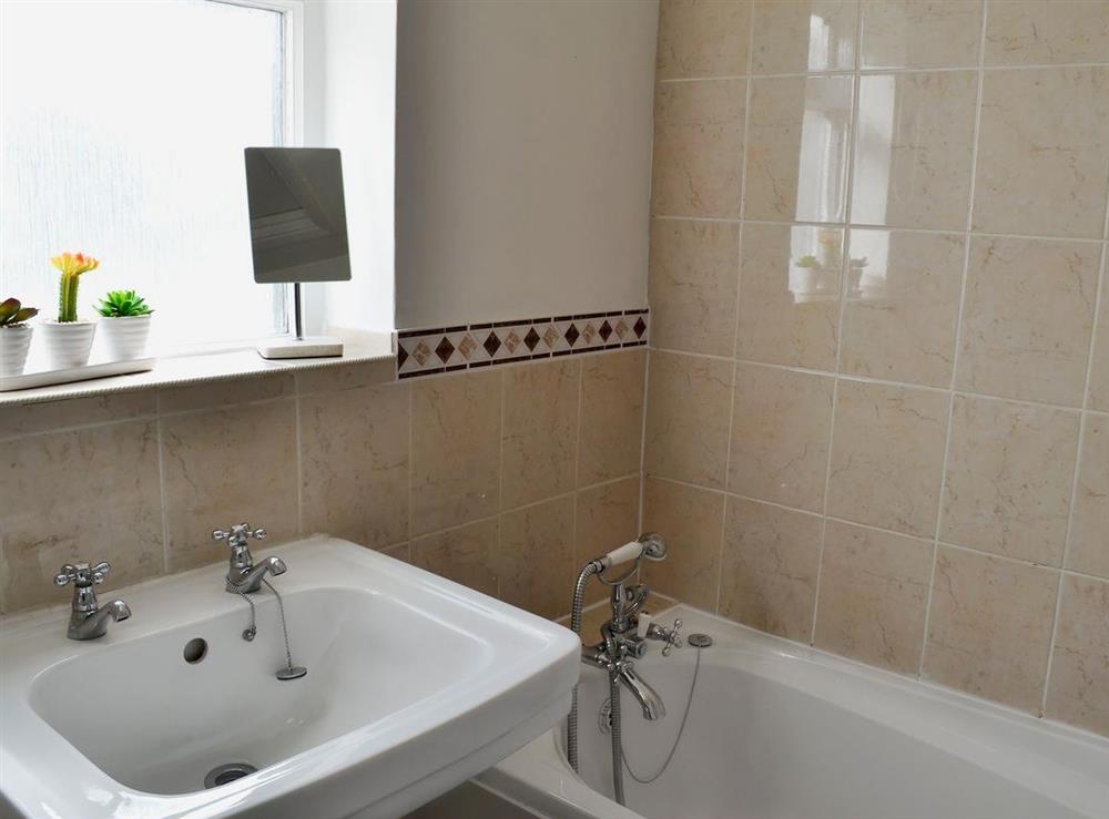 Tiled family bathroom with shower over the bath at Little Birketts Cottage in Holmbury St Mary, near Dorking, Surrey