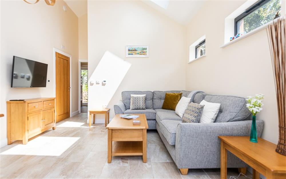 A lovely, light and spacious living area with a corner sofa and Smart TV. at Little Budock in Helford Passage