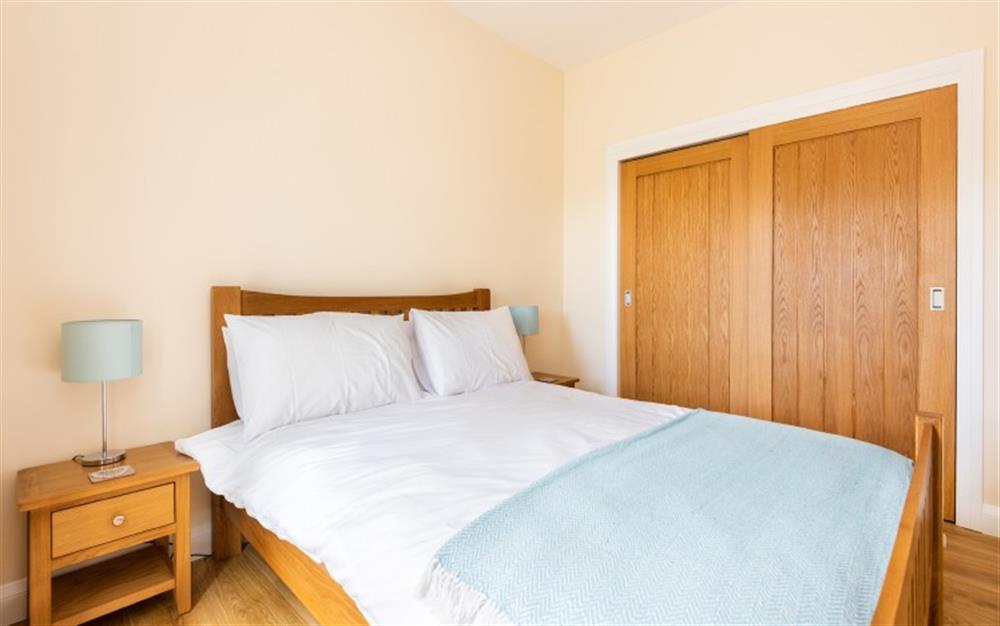 The master bedroom has a large built-in wardrobe. Doors open onto the side patio. at Little Budock in Helford Passage