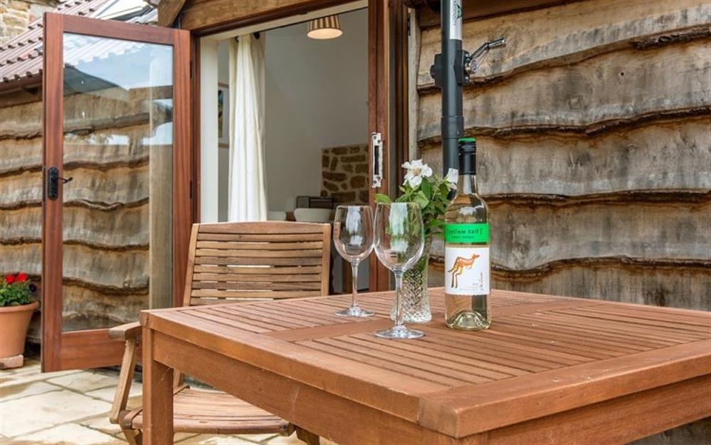 The attractive patio area outside has a wooden dining table and chairs at Little Kershay in Bridport