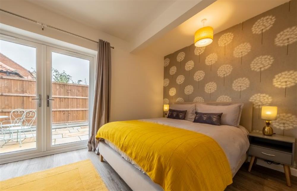 Master bedroom with with a 5’ king-size bed, en-suite shower and double-doors to the courtyard at Little Soames, Holt