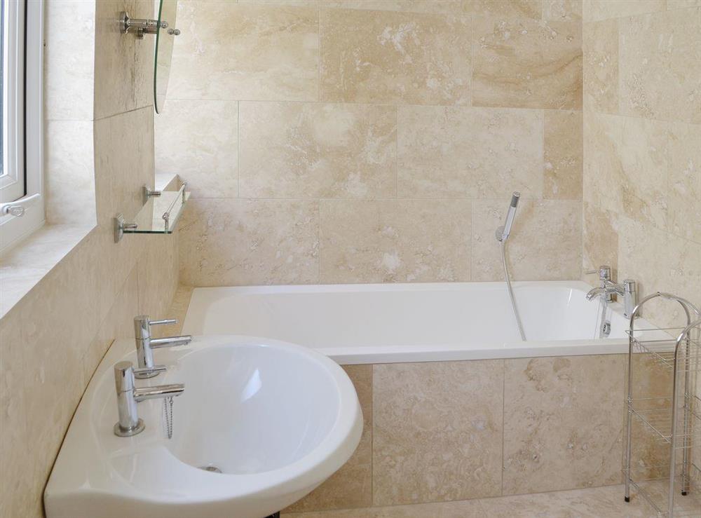 Travertine-tiled wet room with bath at Little Woodlands Amble in Amble, Northumberland