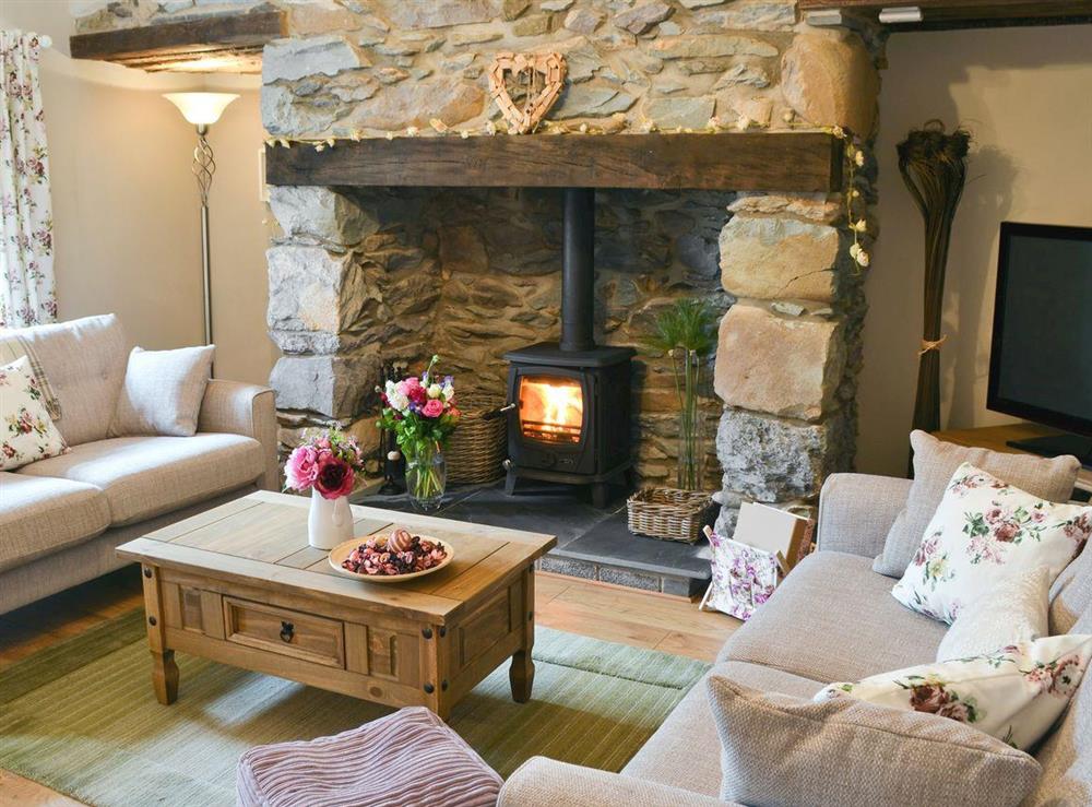 Living room with wooden floor and Inglenook fireplace housing a woodburner at Llifon in Bethesda Bach, near Caernarfon, Gwynedd