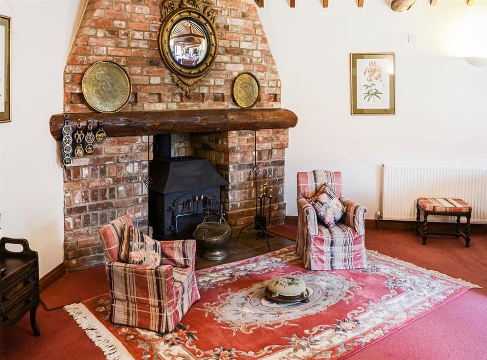 Fireplace is in the corner of the room so that the L-shaped room benefits from the heat that the wood burner throws out. at Lodge Farm Barn in South Walsham, North Norfolk, England
