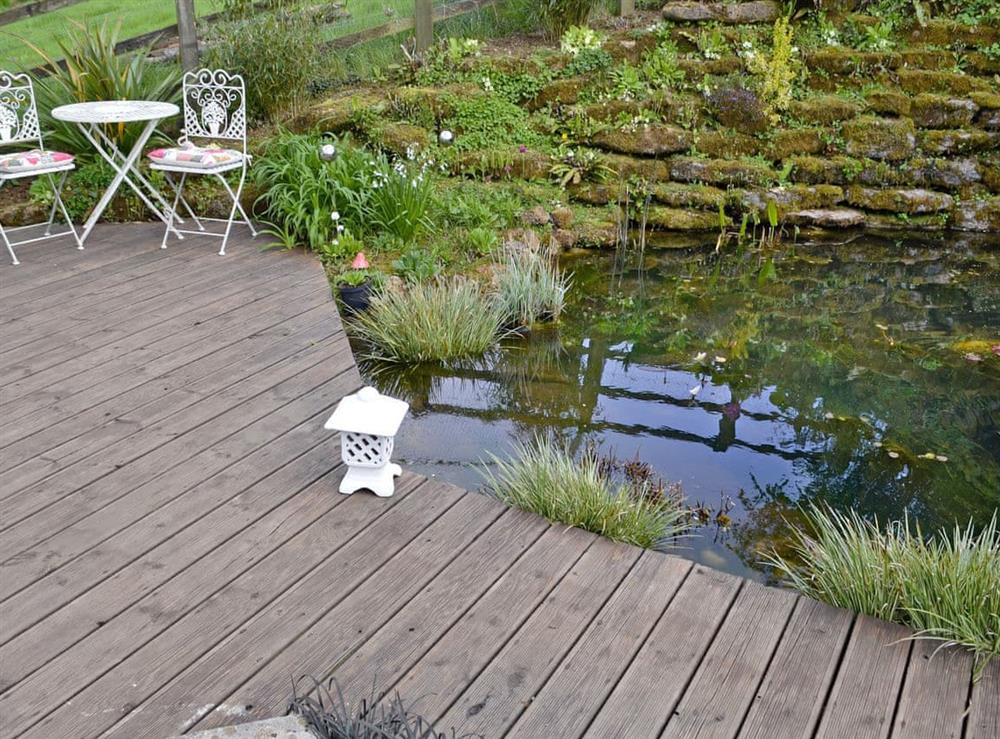 Peaceful decked patio with unfenced pond at Loft by the Pond in Uploders, near Bridport, Dorset