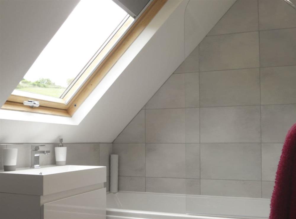 Light and airy en-suite bathroom with shower over bath at The Cob Barn, 