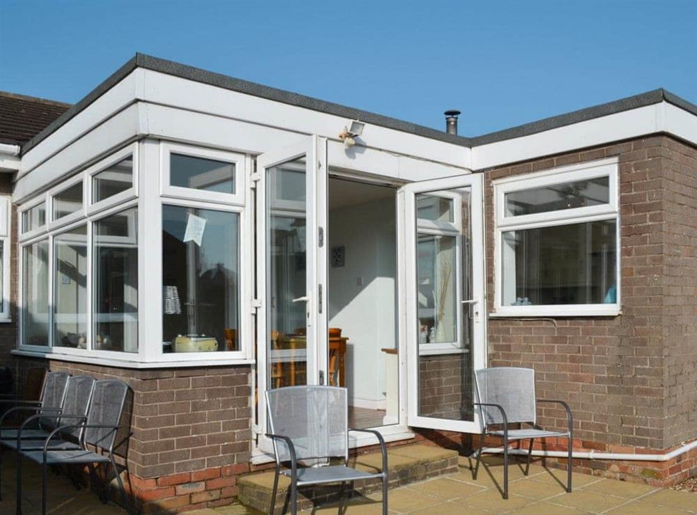Sun room with patio doors and ample seating at Longstone Bungalow in Beadnell, Northumberland