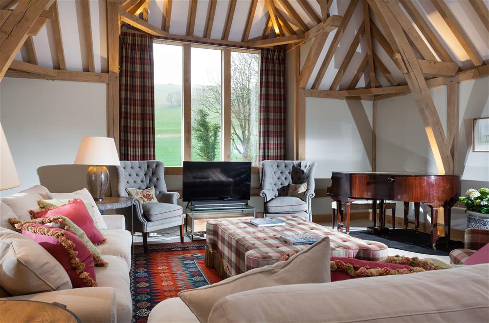 The sitting area with sumptuous seating and exposed oak beams at Lower Farm Barn, Hungerford