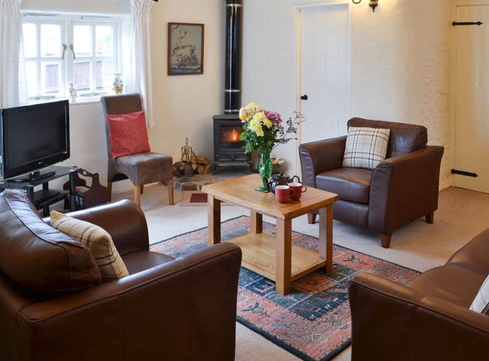 Cosy living room with leather furniture at Lynches in Parkham, near Bideford, Devon