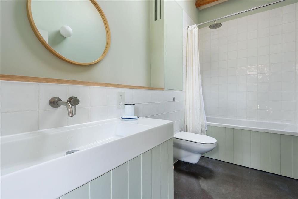 The en-suite bathroom to bedroom one with a bath and overhead shower at Lynchets, Dorchester