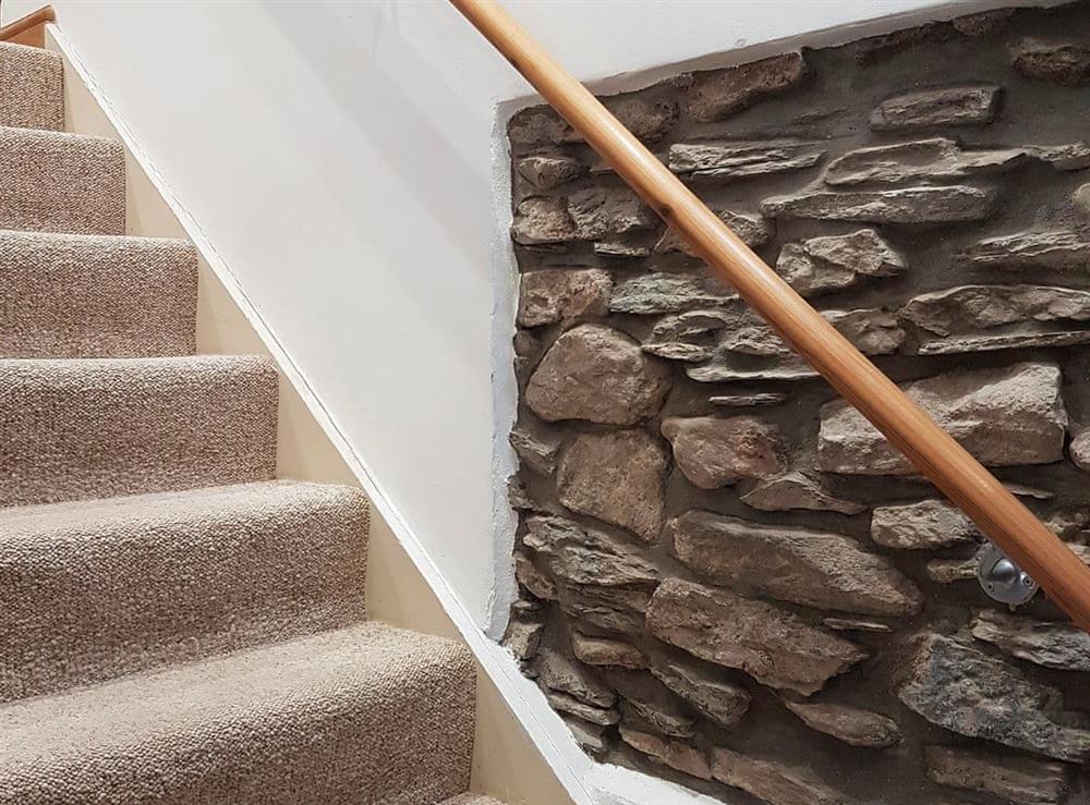 Staircase with exposed stonework and handrail at Lynton Cottage in Combe Martin, Devon