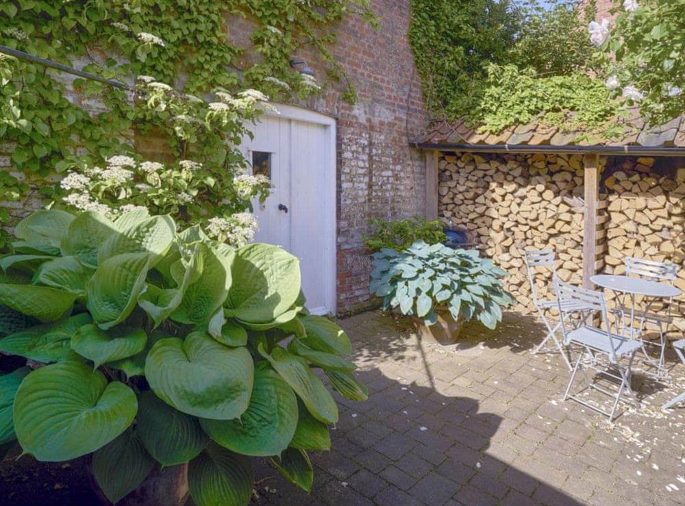 Patio and log store area with outdoor furniture at Madeleine’s Barn in Wells-next-the-Sea, Norfolk., Great Britain