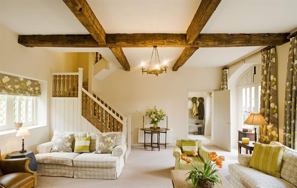 The large, dramatic sitting room with its original beams has two seating areas, with comfortable sofas and chairs and a wood-burning stove (photo 2)