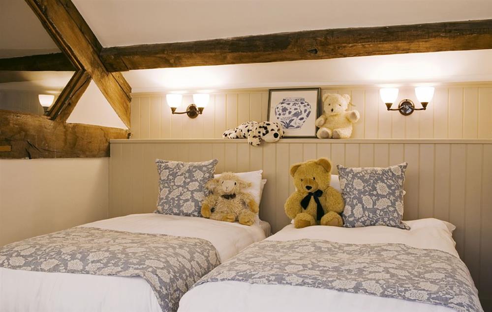 Up the winding second staircase, you enter a warm and cosy twin bedroom at Malbanc Cottage, Whitchurch