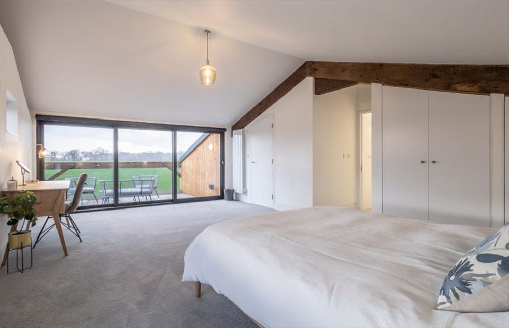 Master bedroom with private balcony overlooking the fields and en-suite shower room at Mandalore, Henham