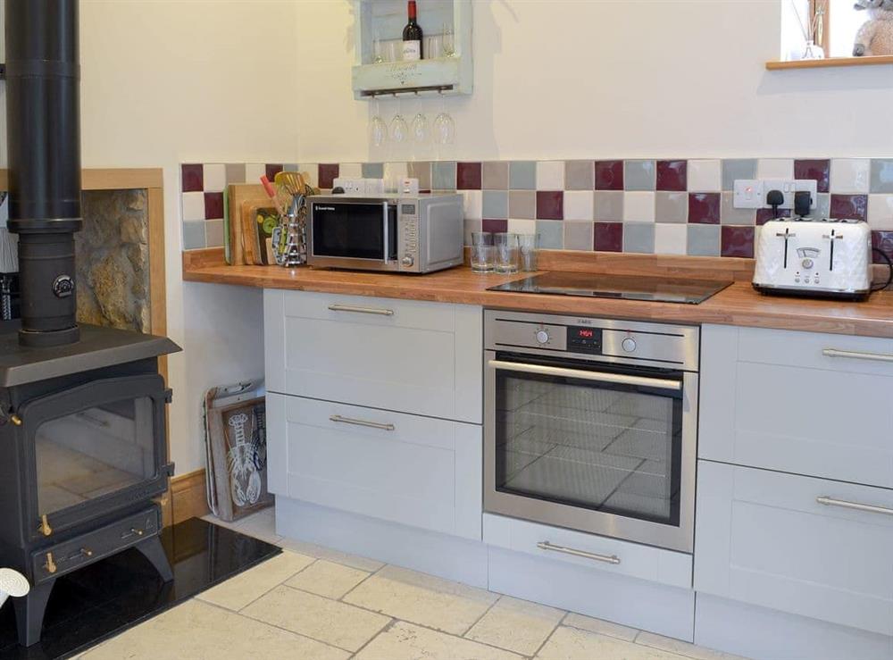 Well equipped kitchen with a cosy wood burner at Manor House Dairy Cottage in East Ayton, near Scarborough, North Yorkshire