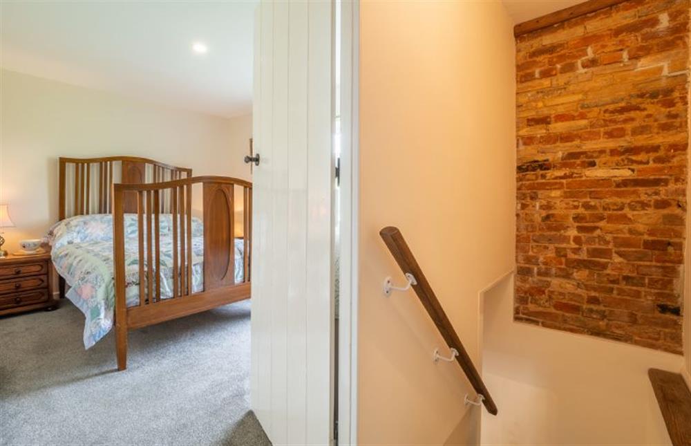 First floor: Top of stairs, with exposed brickwork and view into the master bedroom at Margarets Cottage, Potter Heigham near Great Yarmouth