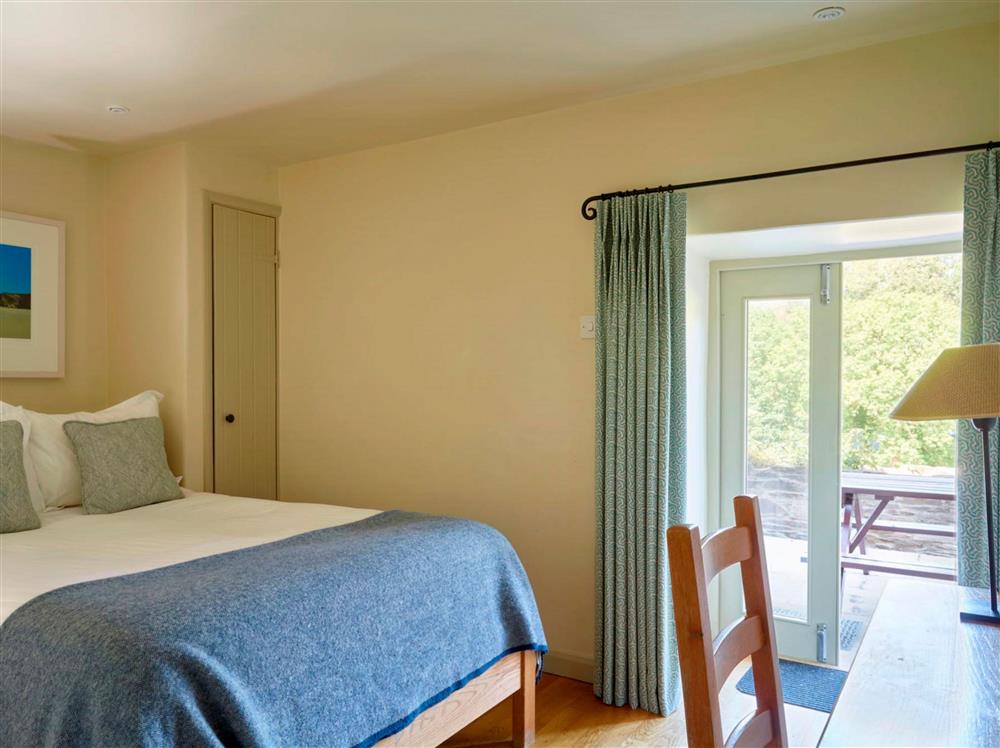 Bedroom one, with a 4’6 double bed and french doors to the patio area at Meavy Cottage, Dartmouth