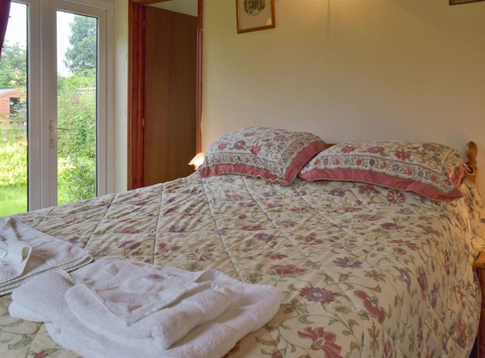 Comfortable double bed with French doors to garden at Mickrandella in Great Yarmouth, Norfolk