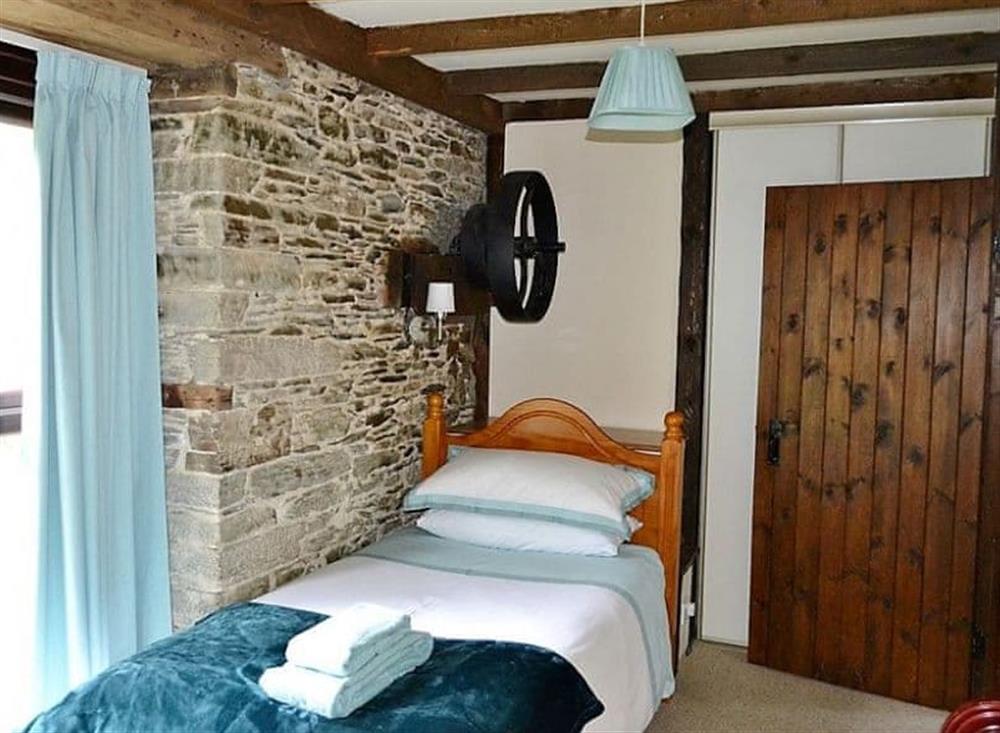 The twin bedroom has large floor to ceiling windows looking out across the garden at Mill Cottage in Fowey, Cornwall