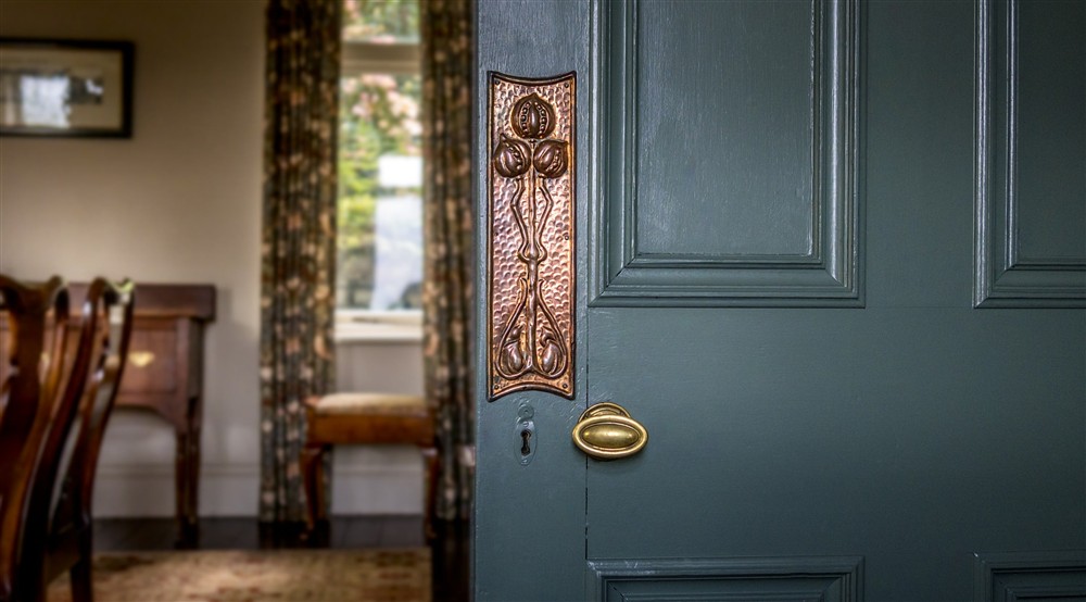 The dining room door with copper work from the Keswick School of Industrial Arts - an original piece from the conversion from the mill to a house - at Millbeck Towers in Keswick, Cumbria