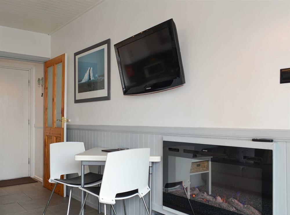 Intimate dining area and wall-mounted TV at Misty Isles Cottage in Oban, Argyll