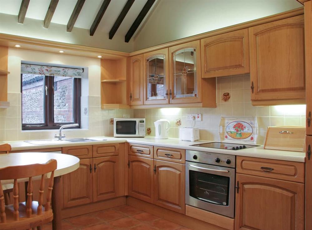 Well-equipped fitted kitchen with exposed wood beams at Littlewoods Barn, 