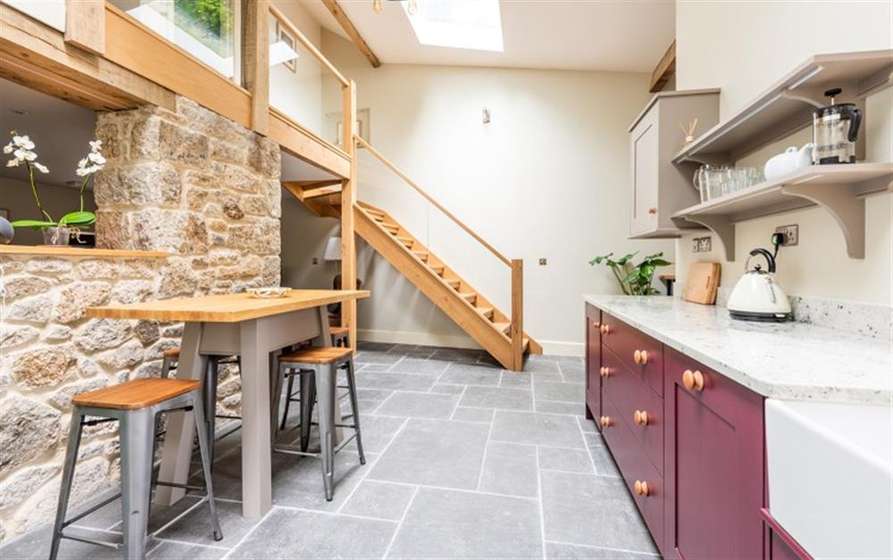 Kitchen with high ceilings and raised table with stool seating at Moorlands Barn in Belstone