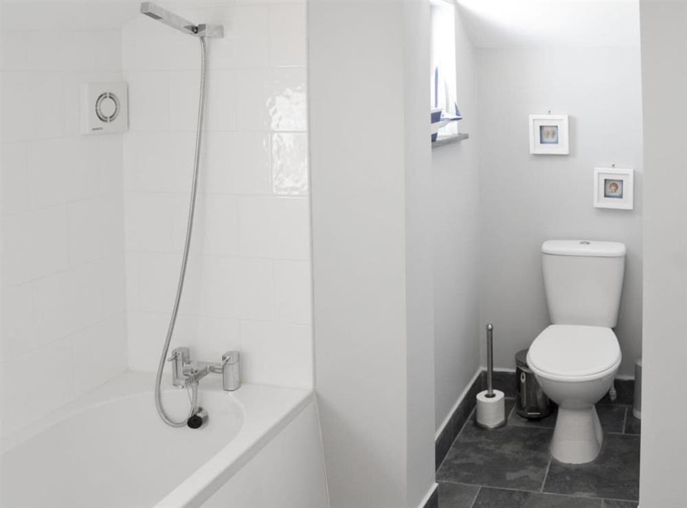 Bathroom with shower over bath, and toilet at Morvoren (Little Mermaid) Cottage in Helston, Cornwall